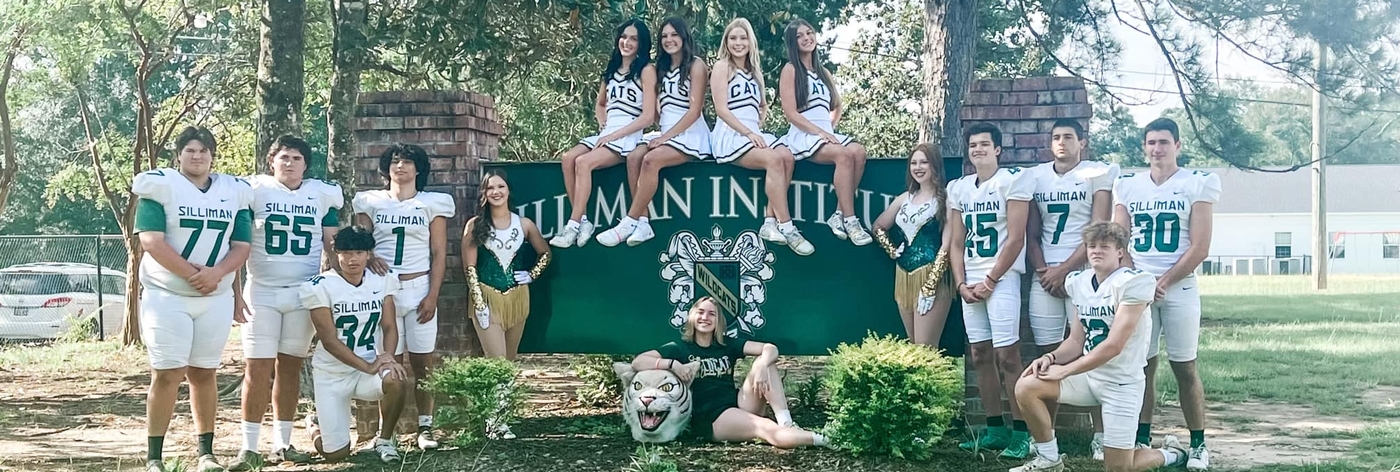 Graduates at the front entrance of the school dressed in athletic attire