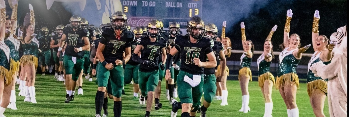 Image of Football players running on to the Silliman Football Field