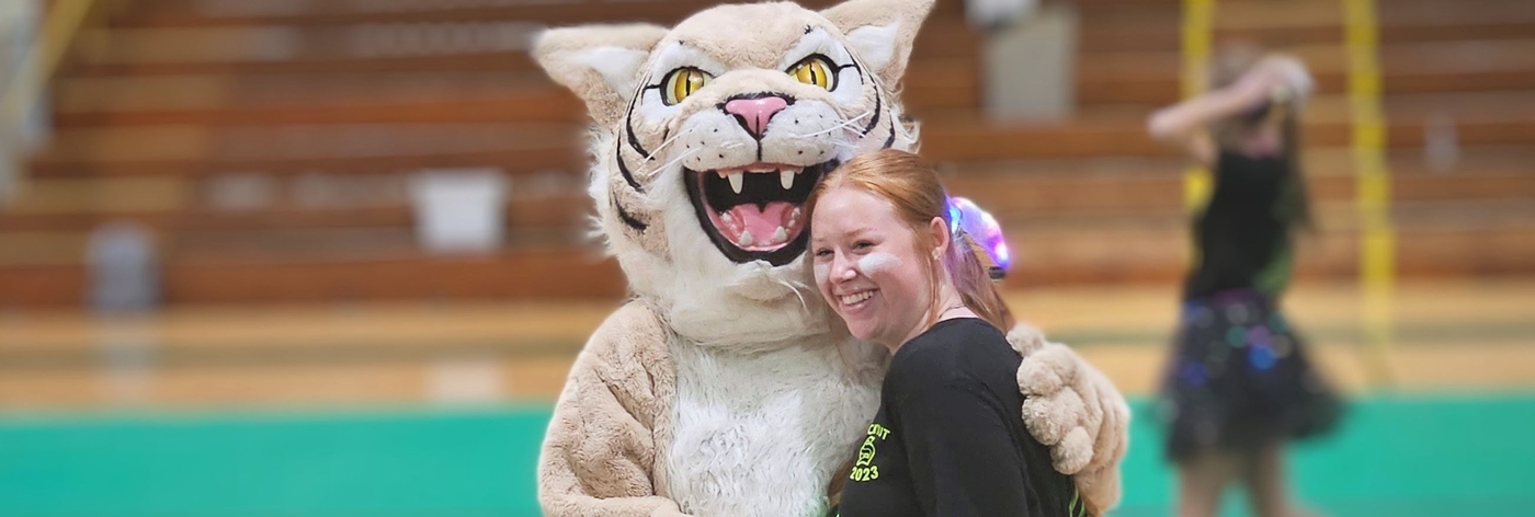 Image of Willie the Wildcat and a student