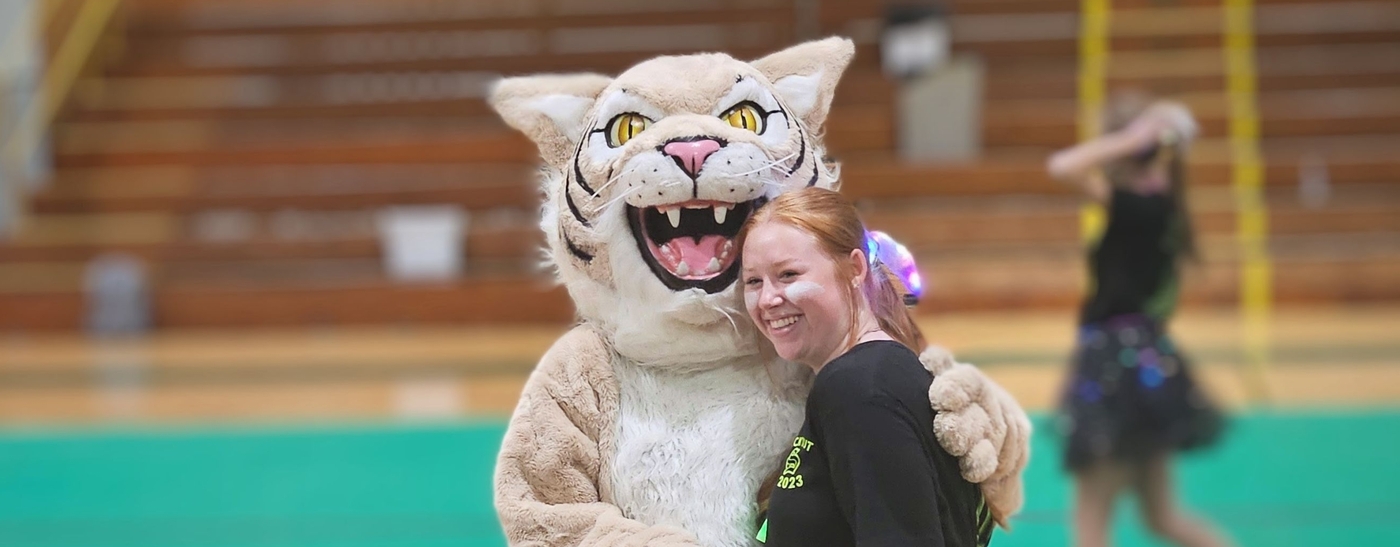 Image of Willie the Wildcats and a fellow student in the gym